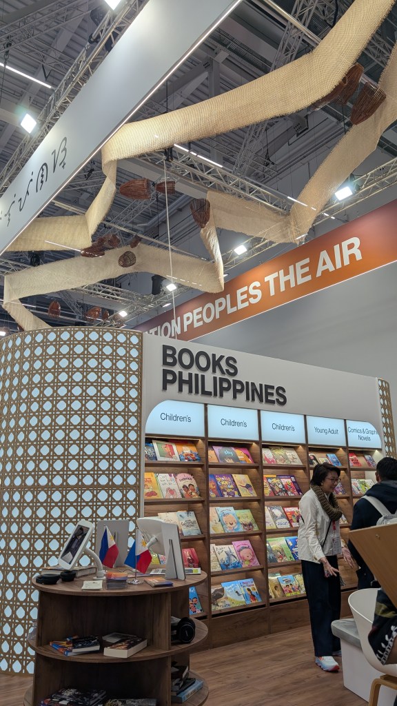 A booth at the Frankfurt Book Fair showcasing Philippine literature with 'Books Philippines' displayed prominently, featuring colorful book covers and visitors engaging with the exhibit.